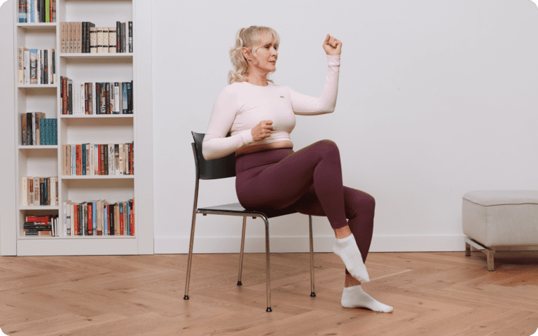 Senior woman practicing gentle chair yoga at home for flexibility and relaxation – safe for over 60